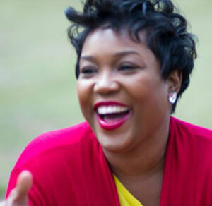 Joyful woman with short curly hair laughing outdoors.
